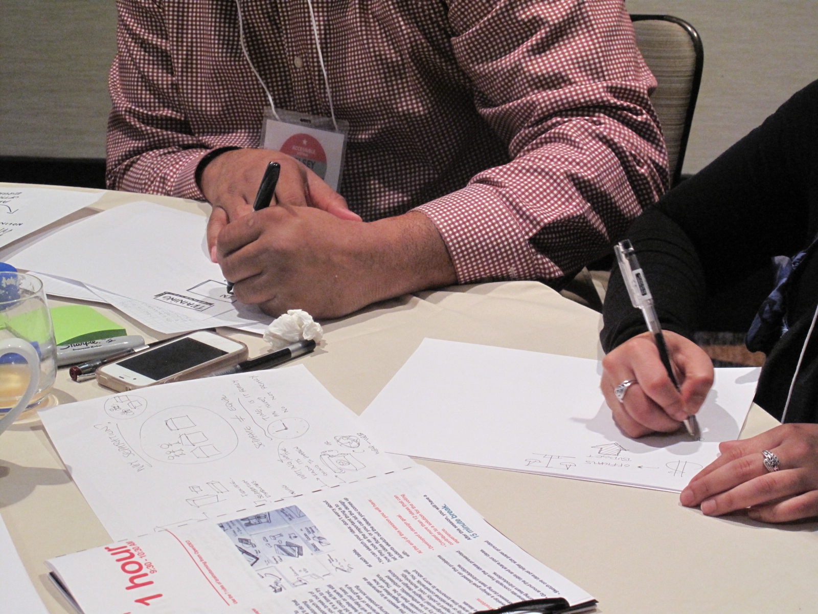 Close up of two people's hands writing on papers.
